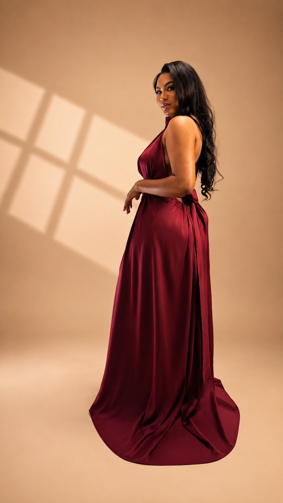 Woman wearing a burgundy floor-length JINNA gown, side view