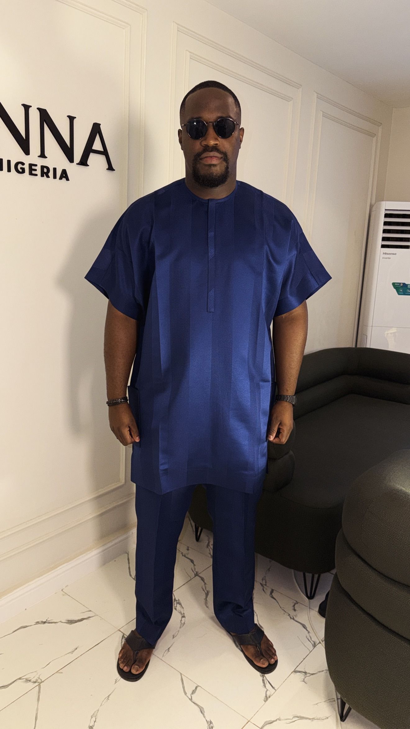 Man in a midnight navy senator set beneath the JINNA Nigeria sign