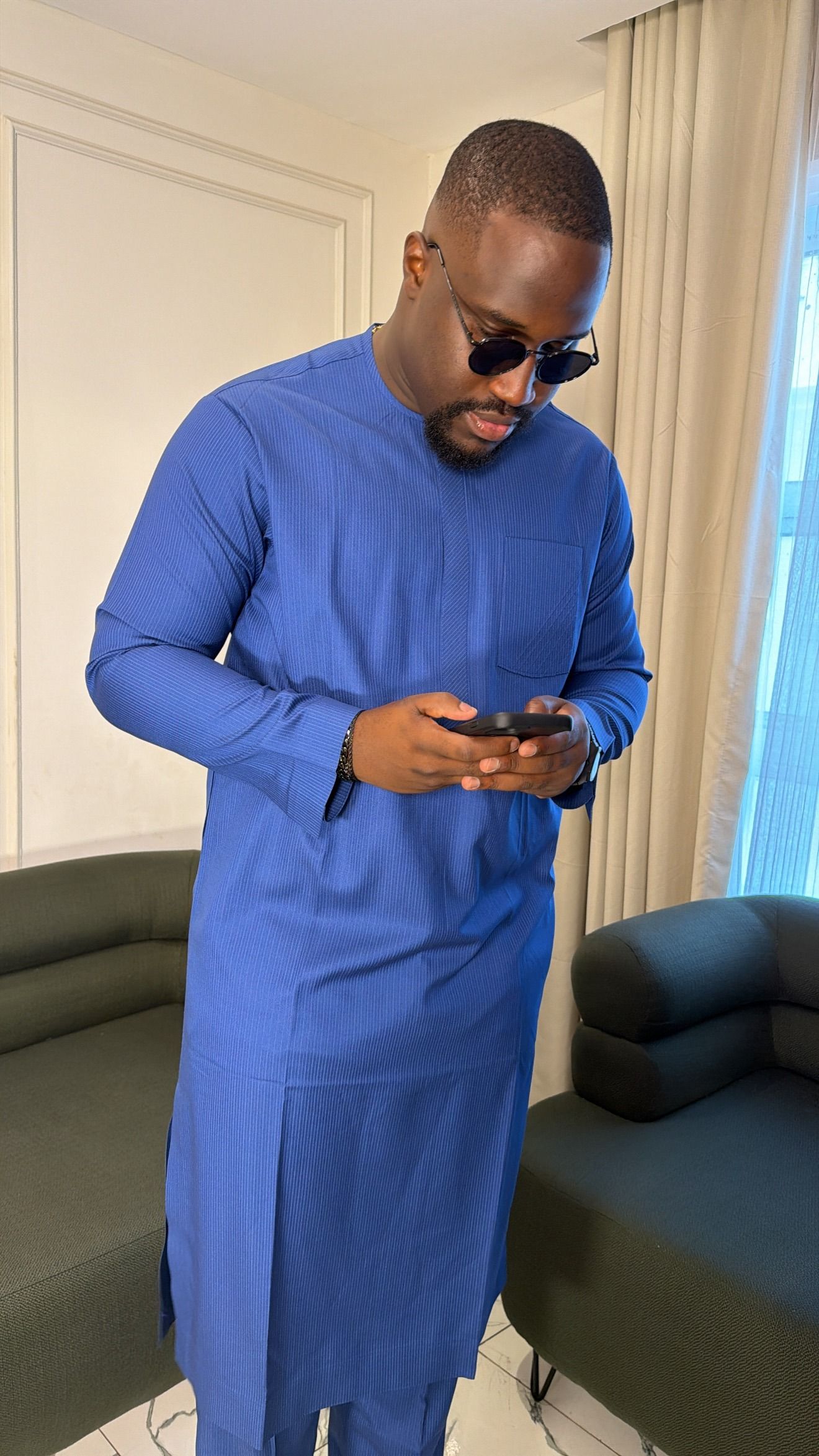 Man in a cobalt blue long-sleeve tunic looking down at his phone